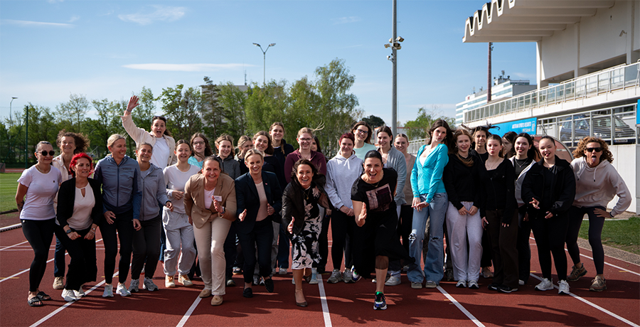 Sport-Staatssekretärin Michaela Schmidt gemeinsam mit Mädchen unterschiedlichsten Alters auf einer Rundbahn in Start-Pose. 