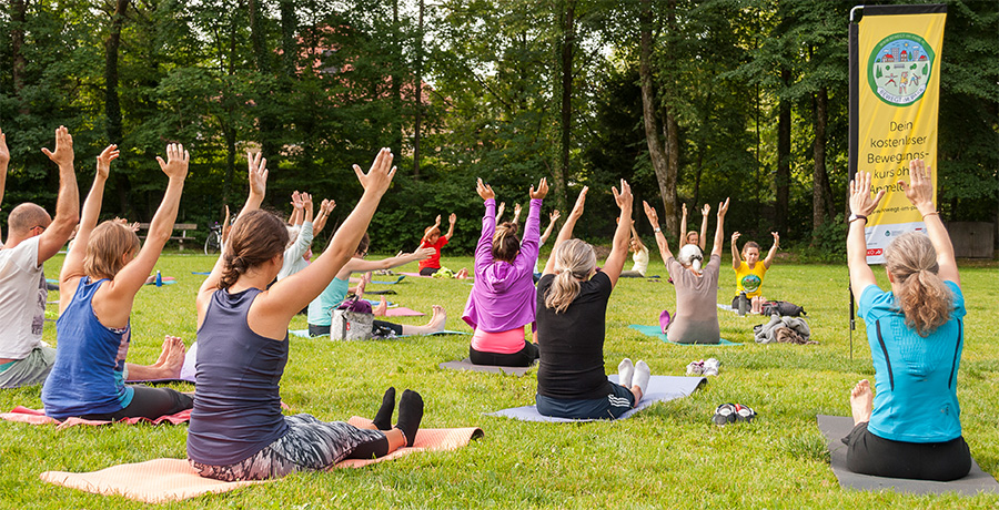 Mehrere Personen auf Yogamatten im Park beim Sport